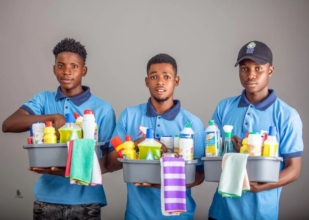 Three cleaning team members holding organised trays of cleaning supplies